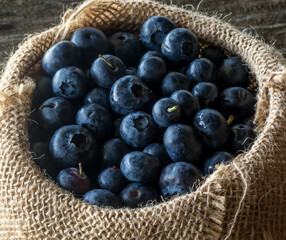 A close up look into a burlap bag filled with fresh blueberries.