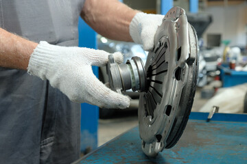 An auto mechanic holds a clutch kit. Compliance and integrity control of the drive disc, the driven...