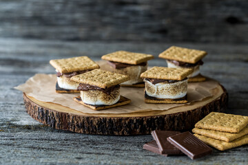 A wooden slab topped with homemade s'mores, ready for eating.