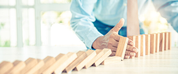 Close-up hand prevent wooden block not falling domino concepts of financial risk management and...