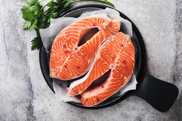 Salmon. Raw salmon steak. Fresh raw salmon fish with cooking ingredients, herbs and lemon prepared for grilled baking on light grey background. Healthy food. Top view. Copy space.