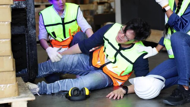 First Aid and safety first. Engineering talking on walki talki radio to employee while his warehouse coworker lying unconscious at industrial factory. Health insurance emergency accident in workplace.