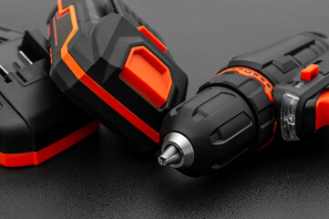 Accumulator drill-screwdriver with battery and charger on black.