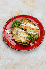stuffed eggplants under cheese in a red plate, vertical photo

