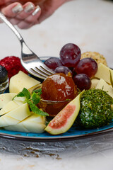 canned fruits and berries with cheese in a blue plate macro photo with a fork
