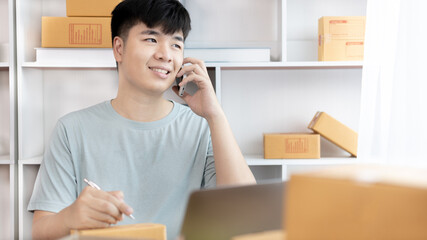 Man selling products online was talking on the phone or chat to receive an order from a customer and list in a notebook, Online shopping SME entrepreneur, Packing box, Sell online, Freelance working.