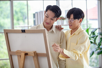 Asain gay couple draw and paint together in the living room of their home, LGBTQ concept.