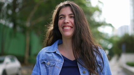 Happy young woman walking outside. A joyful expressive girl smiling going for a walk being carefree