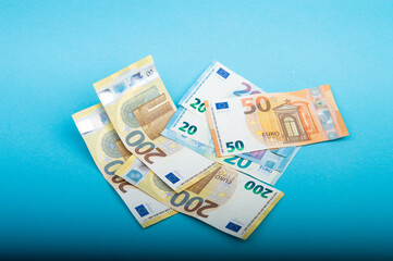 Euro banknotes of twenty, fifty and two hundred on bright blue background