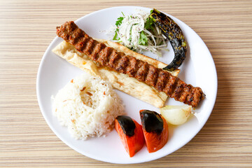 Grilled Turkish Adana, Urfa  Kebab with grilled vegetables, onion and rice on plate. Adana durum .