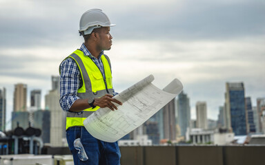 Construction engineer holding a blueprint in his hand is checking the correctness of the building's construction.