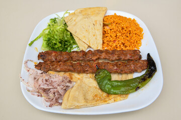Grilled Turkish Adana, Urfa  Kebab with grilled vegetables, onion and rice on plate. Adana durum .