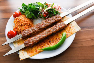 Grilled Turkish Adana, Urfa  Kebab with grilled vegetables, onion and rice on plate. Adana durum .