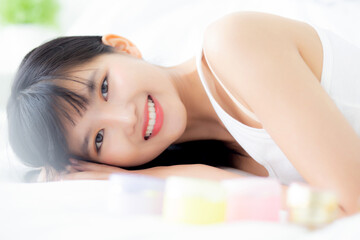 Obraz premium Beautiful of young asian woman smiling and lying on bed at bedroom, beauty of girl with hygiene and healthy, cream and lotion and skin care, cosmetic and makeup, skincare and lifestyles concepts.