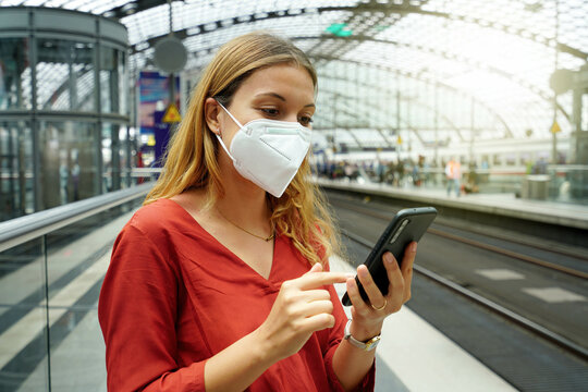 Portrait of young woman with protective face mask using mobile phone at Berlin Central Station on sunset, Germany