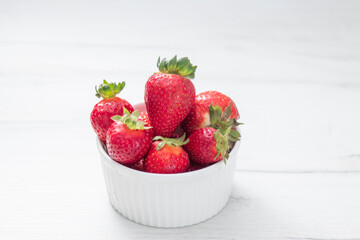 Fresh ripe delicious strawberries in a white bowl on a gray stone background