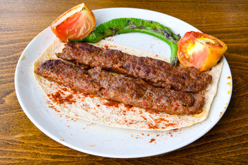 Grilled Turkish Adana, Urfa  Kebab with grilled vegetables, onion and rice on plate. Adana durum .