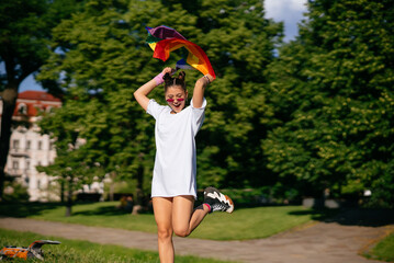 Young woman waving LGBT pride flag in the park.