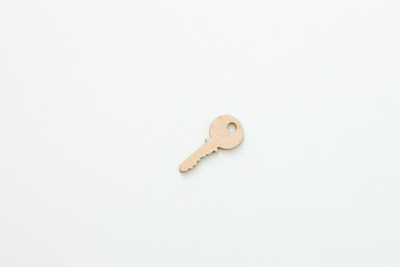 Wooden key on white wooden background, buying new house real estate concept