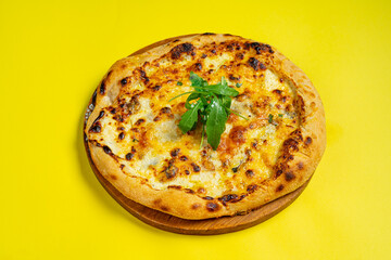 Pizza quattro fromaggi on a wooden board on a yellow background