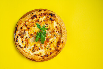 Pizza quattro fromaggi on a wooden board on a yellow background