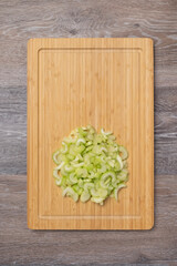 Obraz na płótnie Canvas Stems of fresh juicy celery are sliced on a cutting board with copy space
