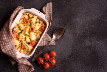 Baked cauliflower cooked with tomatoes and creamy cheese, healthy vegetable meal