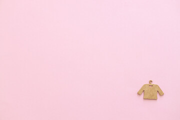 A wooden figure of a clothes hanger on a pink background. Shopping concept