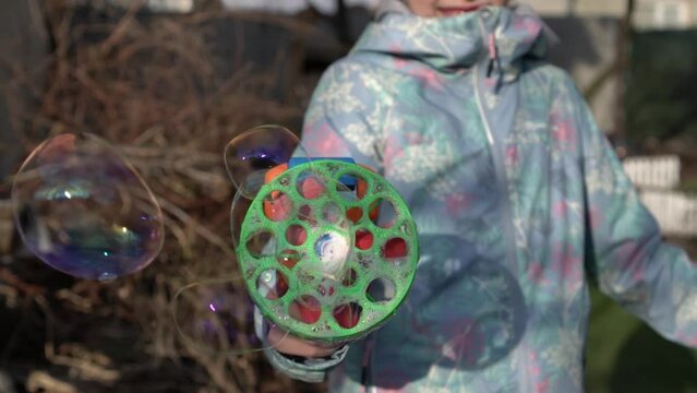 Slow motion of toy bubble gun blowing soap bubbles in child hands
