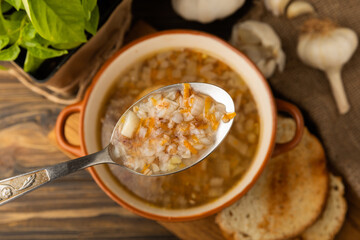 Delicious hot buckwheat soup in a bowl. Composition on brown texture table. Soup with garlic, croutons and spices. Useful and healthy food. Proper nutrition concept. Copy space.
