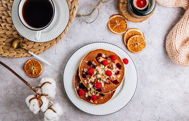 Fresh homemade pancakes with almonds, raspberry and coffee on white kithen background. Cozy breakfast