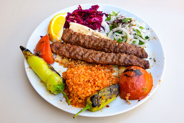 Grilled Turkish Adana, Urfa  Kebab with grilled vegetables, onion and rice on plate. Adana durum .