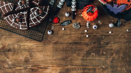 Chocolate cobweb brownies with candy spiders, homemade treats for Halloween on rustic wooden background