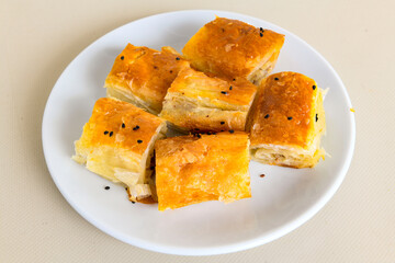 Turkish style meat stuffed filo dough borek served kol boregi. Cheese and minced pie are sliced on a marble background. Turkish name: Kol Boregi, kiymali, peynirli su boregi.