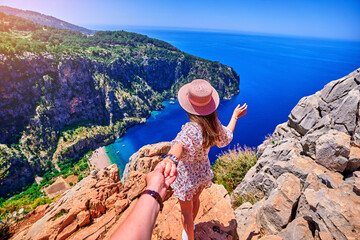 Girl traveler stands on hill rock over blue sea bay in Turkey, butterfly valley. Enjoy holiday vacation and follow me to beautiful traveling places