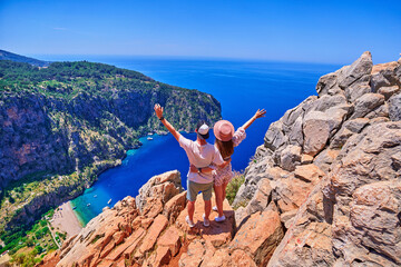 Lovers couple traveler stands together on hill rock over blue sea bay in Turkey, butterfly valley....