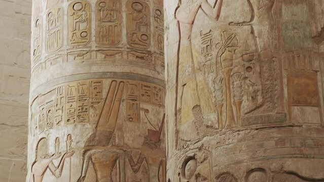 Papyrus columns of Great Hypostyle Hall is located in Karnak temple complex. Famous monuments of Ancient Egypt with inscriptions and reliefs. Antique pillars. Camera movement from top to bottom