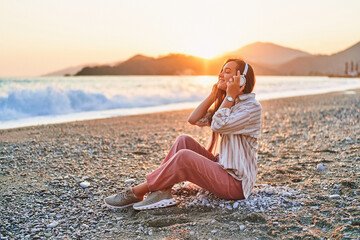 Calm serene alone woman with closed eyes enjoys of listening relax traveling music on the seashore...