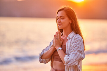 Portrait of calm serene satisfied woman with closed eyes and praying hands enjoys beautiful moment...