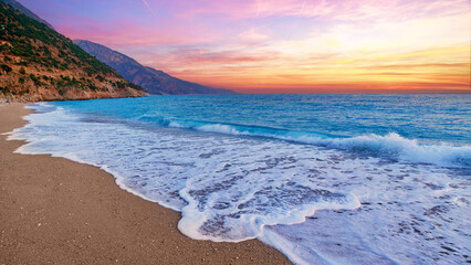 Landscape of beach with idyllic sunset gradient sky and blue sea with white foam