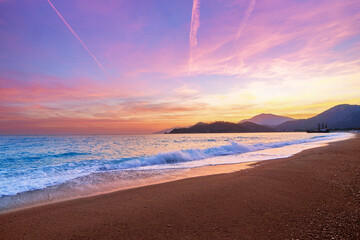 Landscape of beach with idyllic sunset gradient sky and blue sea with white foam