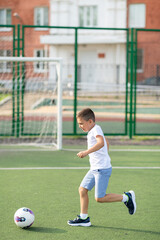 A boy plays football in the school yard