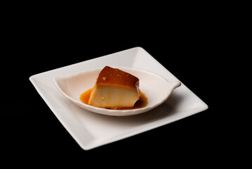 Condensed milk pudding in white plate on dark background