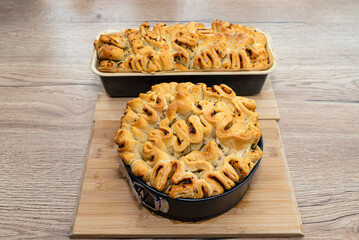 Homemade rectangular and round bread with garlic butter and herbs, in a  baking tin.