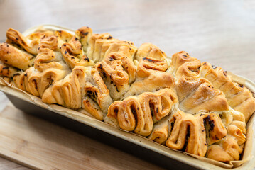 Homemade rectangular bread with garlic butter and herbs, in a  baking tin.