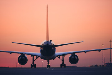 Rear view of airplane taxiing to runway for take off. Traffic at airport at dawn. .