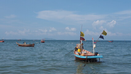 small fishing boat low tide, small boat out to sea with colored flags attached in the sea in Thailand. 