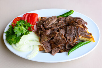 Turkish and Arabic Traditional Ramadan doner kebab with tasty tomato sauce and rice or turkish pilav in white plate on wood table background. ( Pilav ustu doner)