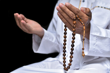 Religious muslim islam man in white session lift two hand for praying to Allah in mosque, isolated on dark background.concept for islamic pray, Ramadan, Eid al Fitr, eid ad-ha, meditation