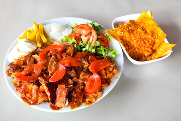 Turkish and Arabic Traditional Ramadan doner kebab with tasty tomato sauce and rice or turkish pilav in white plate on wood table background. ( Pilav ustu doner)
